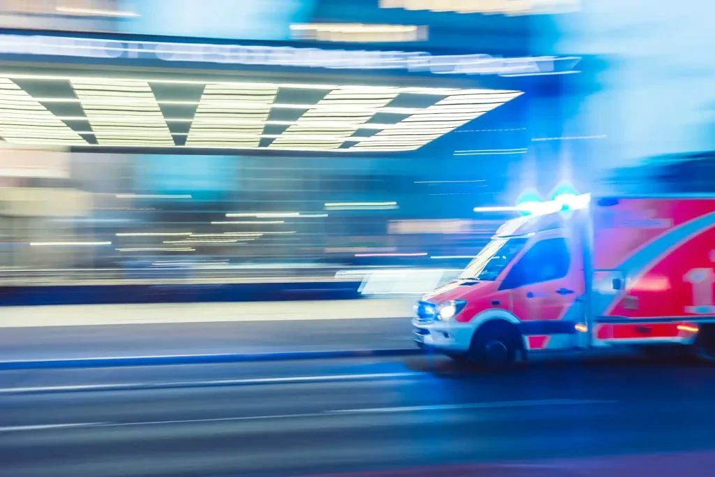 Rettungswagen mit eingeschaltetem Blaulicht, der Notfallmedizinische Dienste und Versicherungsschutz symbolisiert.